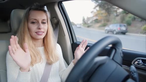 Smiling Woman Waving Inside Car While Driving