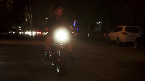 Stylish Brutal Motorcyclist Drives a Bike in the City with Bright Headlight By Street Road in Fog