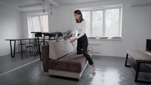 Woman Vacuums Couch in Modern Interior