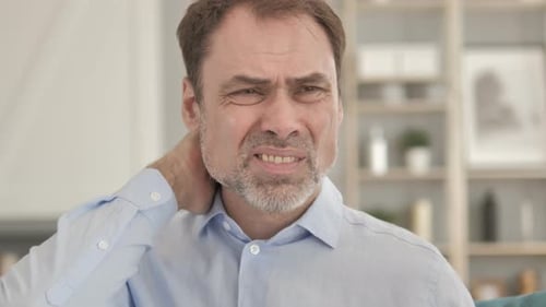 Man Massaging Stiff Neck in Living Room