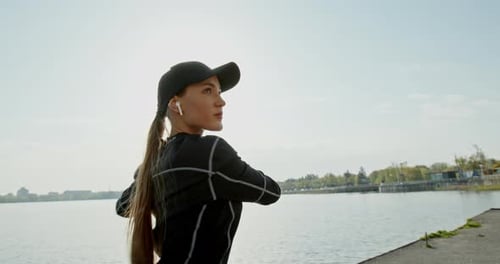 Young Woman Stretching Arms Before Workout by Water