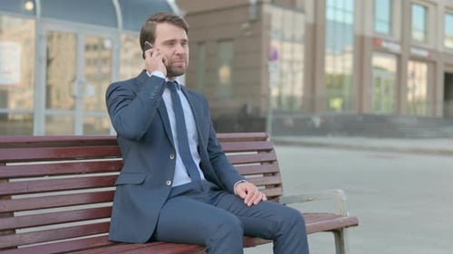 Man in Suit Talking on Cellphone on Bench