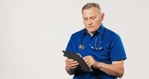 Man in Blue Shirt Using Tablet Indoors