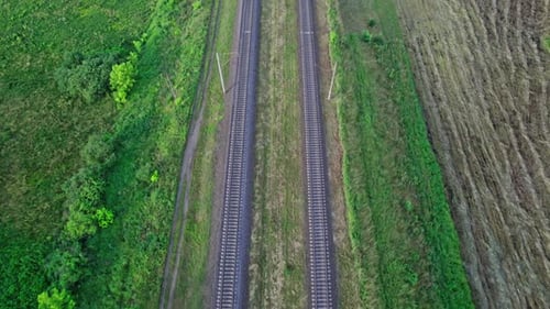 Drohnenaufnahme zeigt Eisenbahnschienen zwischen Feldern