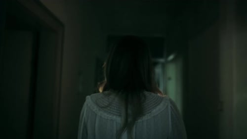 Person Walking Down a Dark Hallway at Night