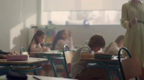 Crianças sentadas em mesas na classe escolar