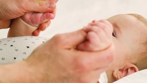 Baby Holding Finger of Adult Lying on Back