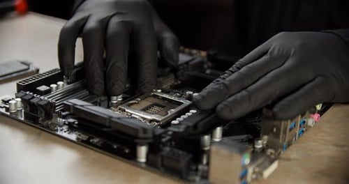 Engineer Repairman Holding Hands in Black Gloves Chip Processor CPU To Insert Into the Socket of the