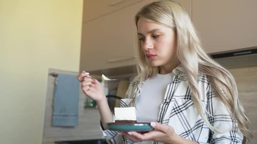 Woman Eating Cake in Kitchen