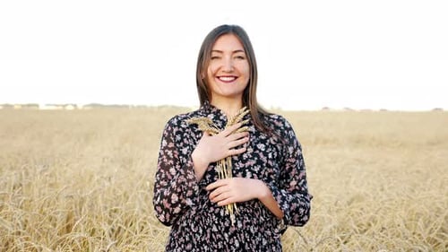 Young Woman with a Bouquet of Ears of Ripe Wheat in the Field