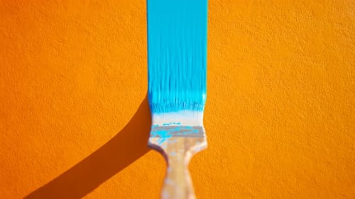 Paintbrush Painting Blue Stripe on Orange Surface