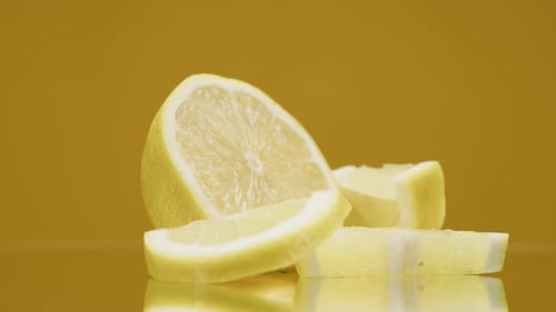 Closeup of Rotating Ripe Lemon Pieces on Yellow Background Making a Cocktail of Citrus Fruits