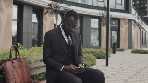 Businessman Using Smartphone Sitting on Bench