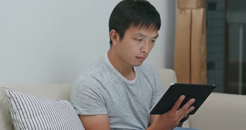 Man Using Tablet Device While Sitting on Couch
