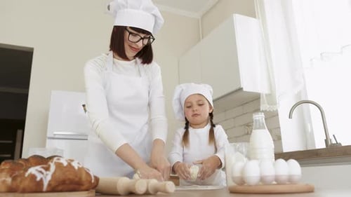 Mãe e filha caucasianas assam juntas, fazem massa e usam os ingredientes necessários