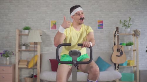 Man Riding Exercise Bike at Home Gives Thumbs Up
