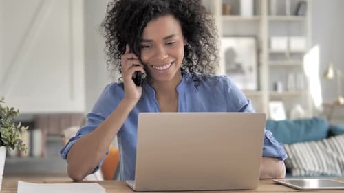 Woman Talking on Phone While Using Laptop