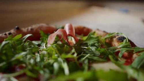 Adding Prosciutto to Fresh Pizza With Arugula