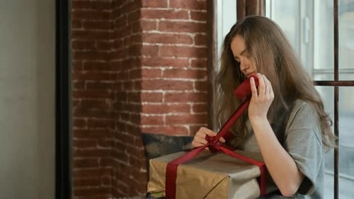 Woman Unwrapping a Birthday Gift Indoors