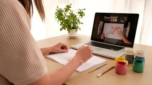 Young Adult Painting at Desk with Laptop