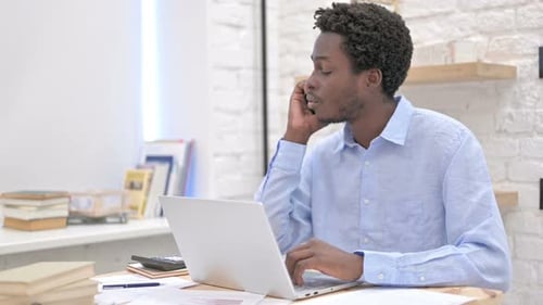 Worried African Man Talking on Phone