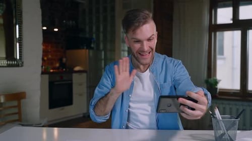 Man Chatting on Phone During Video Call at Home