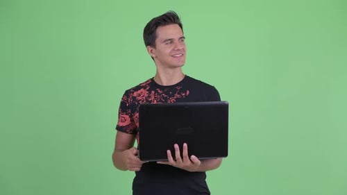 Man Smiling, Holding Laptop Against Green Screen