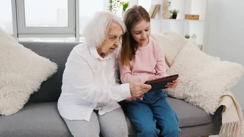 Grandmother and Child Use Tablet Together on Couch