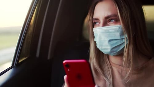Woman Wearing Mask Riding in Car with Phone