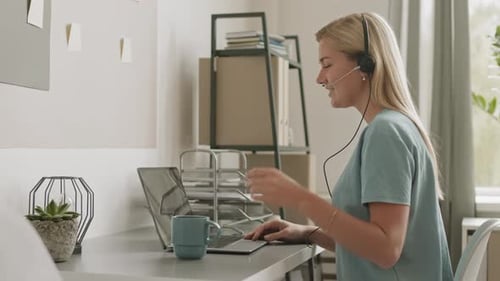 Woman with Headset Using Laptop for Video Call