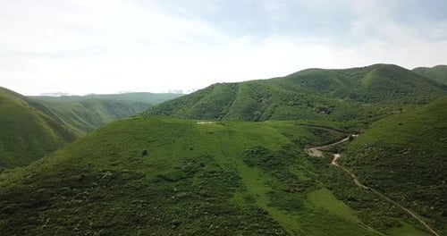 Paraglider Soaring Over Green Mountain Landscape