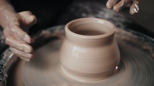 Homme Potter travaillant sur une roue de potier faisant un pot en céramique à partir d'argile dans un atelier de poterie