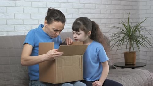 Woman and Child Opening Cardboard Box on Couch
