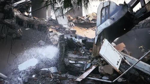 Bulldozer Demolishing a Building with Water Spraying