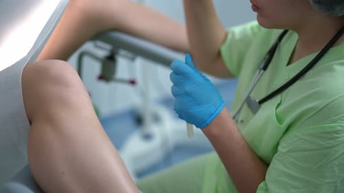 Side View Unrecognizable Gynecologist Taking Probe As Woman Lying with Legs Parted on Gynecological