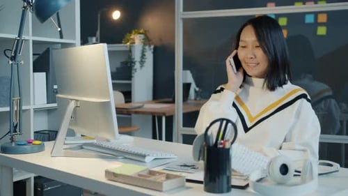 Friendly Asian Businesswoman Speaking on Mobile Phone Discussing Business Working in Office in