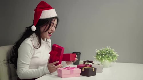 Woman Wearing Santa Hat Opening Christmas Gift