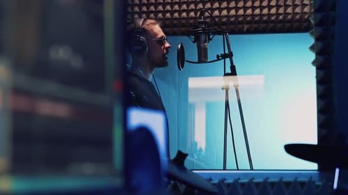 Singer with Headphones and Sound Engineer Works in Professional Recording Studio