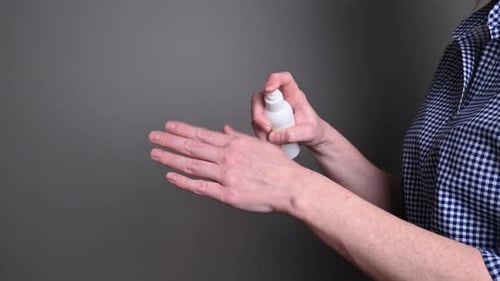 Adult Applies Hand Sanitizer from Spray Bottle