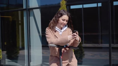 Young Woman Using Phone With Electric Scooter