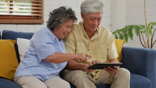 Senior Couple Using Tablet Together on Cozy Sofa