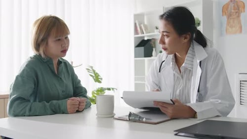 Young Asian female doctor is delivering great news talk results with girl patient hospital