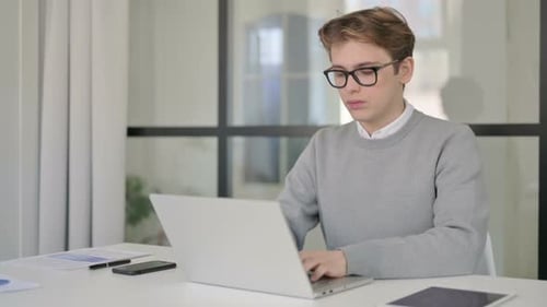Junger Mann schließt Laptop und verlässt das moderne Büro