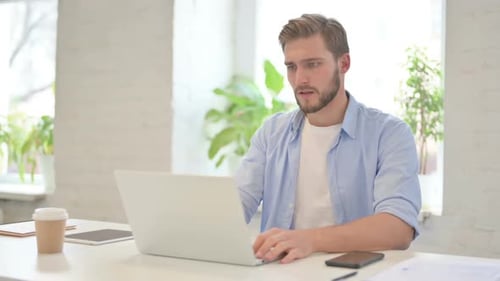 Man Working at Laptop Shows Frustration