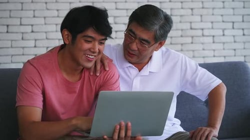 Young Adult and Adult Share Laptop on Couch