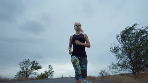 Athlete Woman in Sportswear Trains Running on Road Outdoor Background Cloudy Sky Low View