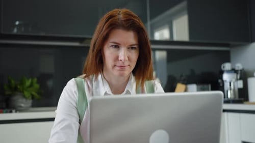 Woman Working on Laptop in Modern Kitchen