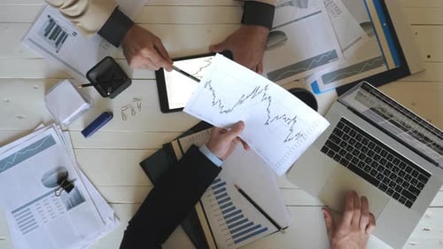 Top View Male Hands of Two Businessmen Looking and Examining Graphs with Financial Reports in Office