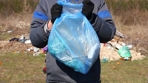 un voluntario sostiene una bolsa de basura frente a él