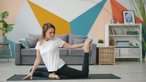 Woman Practicing Yoga Stretch on Mat at Home